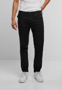 Jeans negri slim-fit din bumbac, cu un design clasic cu cinci buzunare, cusături subtile și fermoar, asortați cu sneakerși albi.