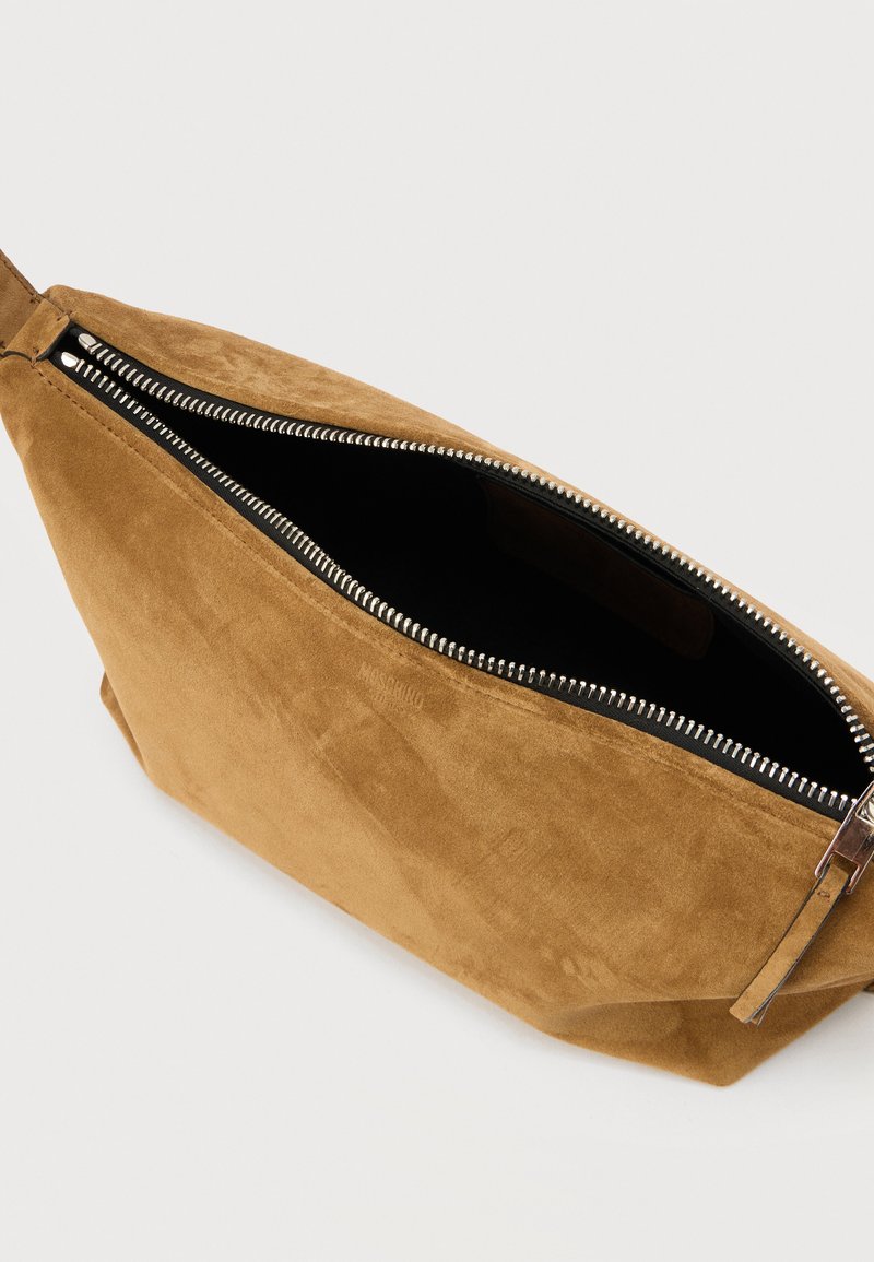 Brown suede pouch with a partially open silver zipper showing a black fabric interior, positioned on a light surface.