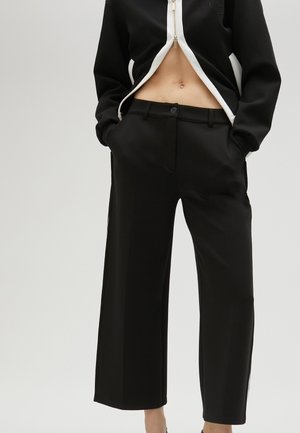 Black wide-leg trousers made of smooth fabric, featuring a tailored fit, front pockets, and a button closure.