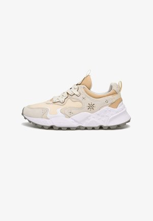 Beige og creme sneakers med nubuck- og mesh-teksturer, der har en kraftig hvid sål med grå skridmærker og dekorativ syning.