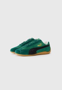 Pair of green suede Puma sneakers with black side stripe, gum rubber soles, and gold logo on the outer side, shown against a white background.