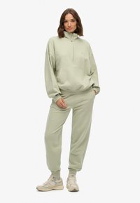 Lys grøn fleece pullover med halv-zip krave, frontrum pocket og matchende tætsiddende sweatpants med ribbede ærmer og ankelbånd.