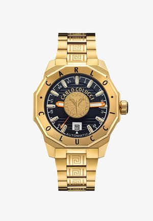 Gold-tone automatic watch with octagonal case, navy dial, textured band featuring Greek key pattern, and a date display at 6 o'clock position.