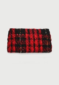 Textil de cuadros rojo y negro, con una superficie texturizada y variaciones en el grosor del hilo, enrollado en una forma compacta.