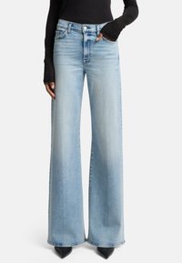 Lichtgewassen wijde jeans gemaakt van denim, met een hoge taille, subtiele vervaging en een schone zoom. Gecombineerd met spitse zwarte hakken.