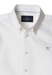 Camicia bianca con bottoni realizzata in cotone. Presenta un logo ricamato blu sul petto e un colletto interno a contrasto. Tessuto leggermente texture.