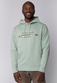 Hoodie vert menthe avec un motif de poisson imprimé et le texte "Niedliche Sardelle". Il dispose d'une capuche avec cordon de serrage et d'une poche kangourou à l'avant.
