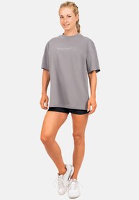 Grijze oversized t-shirt van zacht materiaal, met een ronde hals en korte mouwen. Witte logo-detail op de voorkant.