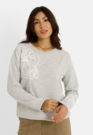 Sweatshirt gris clair avec un motif floral brodé en blanc sur le côté gauche. Doté de manches longues et d'un col rond. Texture douce.