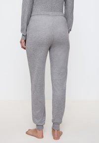 Grå, stickade sweatpants med avslappnad passform, som har elastisk midja och muddar vid anklarna. Slät yta, utan mönster eller dekorationer.