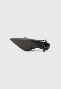Escarpin noir à bout pointu avec bracelet de cheville, présenté vu du dessous sur un fond blanc uni.