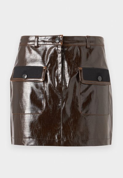 Mini-jupe en similicuir marron foncé brillant avec fermeture à boutons sur le devant et deux poches à rabat en tissu noir.