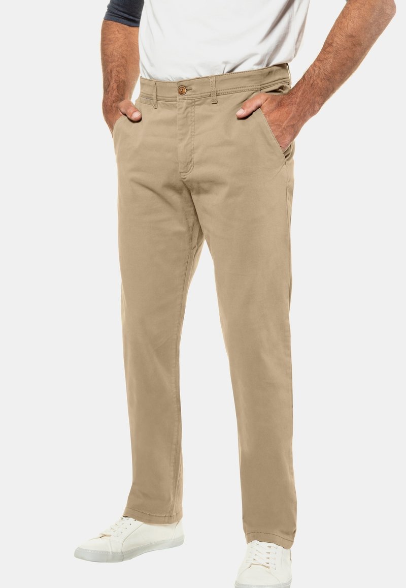 Beige chinos dengan desain kaki lurus, terbuat dari katun, dilengkapi dengan penutupan kancing, loop sabuk, dan saku samping. Dipadukan dengan sepatu sneakers putih.