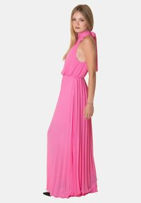 Abito maxi senza maniche rosa con design plissettato, vita arricciata e dettaglio al collo con fiocco. Tessuto morbido con una silhouette fluida.