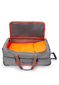 Sac de voyage gris avec accents orange. Grande ouverture révélant un intérieur orange. Comprend des poignées robustes et une poignée rétractable.