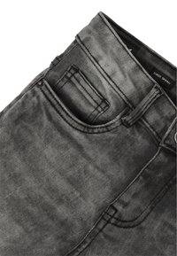 Jeans super ajustados en denim negro desgastado. Presentan un bolsillo frontal, costuras visibles y un botón de metal en la cintura.