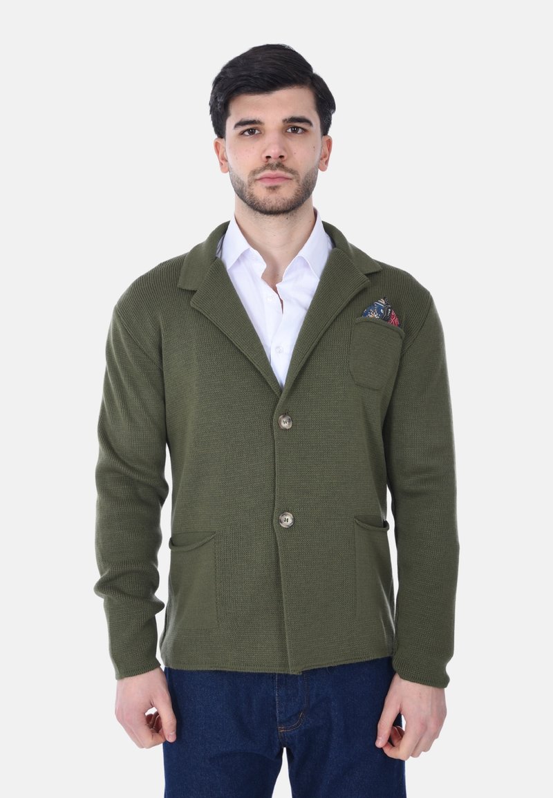 Cardigan lavorato a maglia verde oliva con colletto a scialle, due tasche frontali, chiusura con un solo bottone e un fazzoletto decorativo con motivo.
