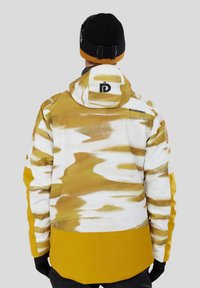 Herre vandtæt jakke med et gult og hvidt abstrakt mønster, hætte og sorte logoaccents på ryggen, med en ensfarvet gul nederdel.