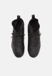 Zapatillas deportivas negras con un acabado texturizado, diseño de tobillo bajo, cordones redondos y forro de tela. Presentan una lengüeta en cada talón.