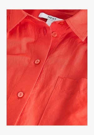 Rotes, kurzärmliges Hemd mit Knöpfen aus leichtem Stoff. Verfügt über eine Brusttasche und passende Knöpfe. Das Etikett trägt die Aufschrift "NEXT."