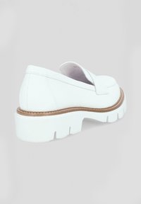 Biały skórzany but wsuwany z masywną białą podeszwą, z przeszyciami i małą ozdobą z przodu.