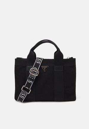 Zwarte stoffen handtas met twee handvatten en verstelbare zwart-witte band met tekst "GUESS" en driehoekig logo aan de voorkant.