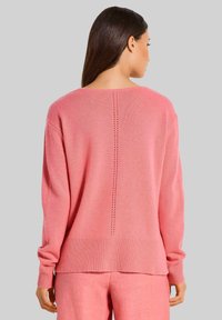 Rosa gestrickter Pullover mit Rundhalsausschnitt, überschnittenen Schultern und gerippten Bündchen. Verfügt über eine vertikale Nahtdetail entlang des Rückens.