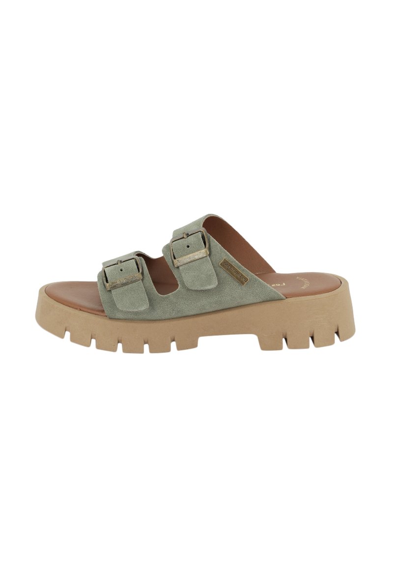 Groene suède slippers met twee verstelbare gespsluitingen, een dikke, gestructureerde beige zool en een gladde bruine voetbed.