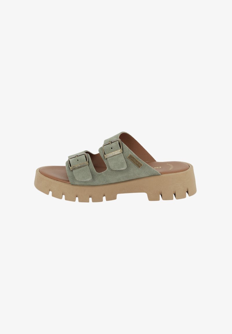 Groene suède slippers met twee verstelbare gespsluitingen, een dikke, gestructureerde beige zool en een gladde bruine voetbed.