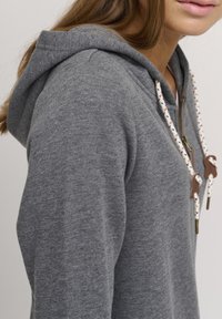 Felpa grigia con cappuccio, dal texture morbida, dotata di zip frontale e cordini decorati con inserti in pelle. Design aderente e casual.