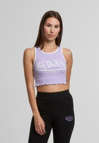 Lila kort tanktopp med scalloped nederkant, med vit "Von Dutch" logotyp; kombinerat med svarta leggings med logotyp på låret.