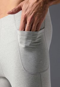 Des leggings en tissu extensible gris avec une poche latérale, une texture lisse, des coutures plates et une coupe ajustée. Idéaux pour les vêtements de sport.