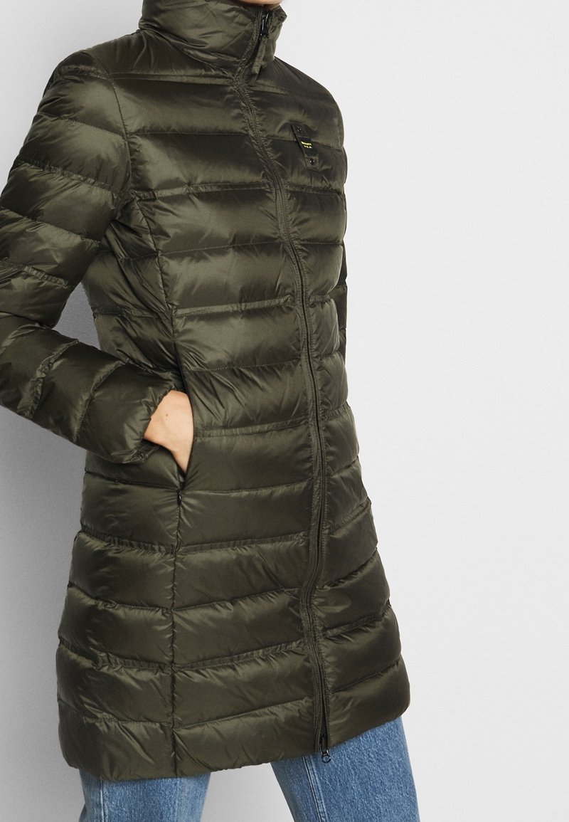 Green puffer coat with a high collar, horizontal quilting, zip closure, and side pockets, made from shiny, smooth material.