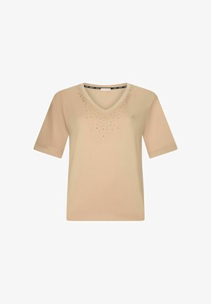 Bēša īsrokastu V veida kakla krekls ar mazām metāliskām kniedēm, kas izkārtotas gradienta rakstā ap kakla izgriezumu.