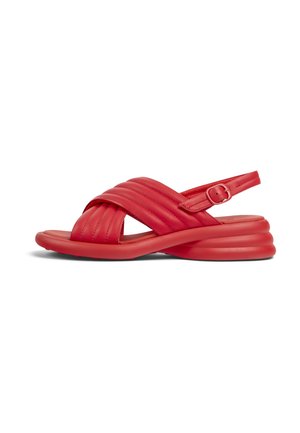 Sandalias rojas con un diseño de tiras cruzadas acolchadas, hebilla ajustable y suela redondeada y estratificada. Textura suave con un acabado brillante.