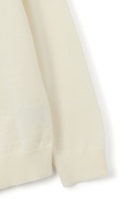 Maglione color crema con una texture morbida, polsini e orlo a coste. Tessuto leggero con una finitura liscia. Senza motivi o dettagli visibili.