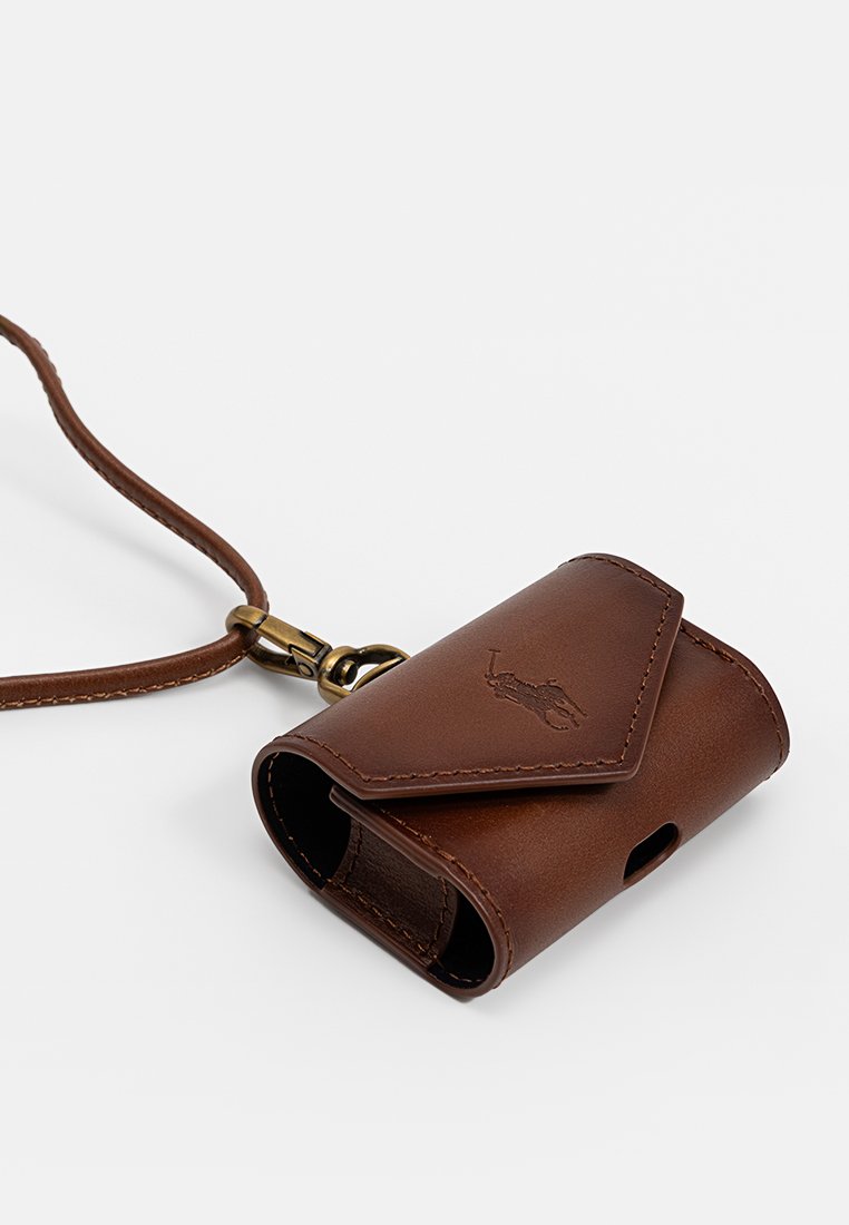 Custodia in pelle marrone con chiusura a pattina, dotata di un anello per portachiavi e apertura laterale per un facile accesso. Texture liscia e dettaglio del logo impresso.