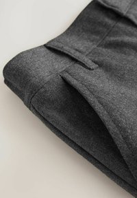 Graue Stoffhosen, ordentlich gefaltet. Das Material wirkt weich mit einer subtilen Textur. Verfügt über Taschen und eine Nahtdetails entlang der Kanten.