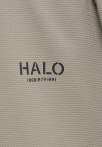 Beżowa tkanina o fakturze z czarnym napisem "HALO" i serią cyfr "196819721981" nadrukowanych poniżej.