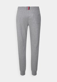Calças de sweat cinza claro com cintura elástica, laço de tecido vermelho, branco e azul na parte de trás, tornozelos com punhos e um pequeno bolso na parte de trás do lado direito.