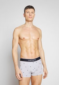 Sivi bombažni bokserji z morsko modrim pasom z logotipom Lacoste, z majhnim morsko modrim vzorcem krokodila po celi površini.