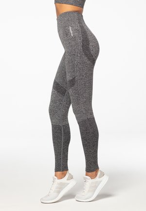 Szare legginsy z teksturowanymi panelami, wysokim stanem i bezszwowym fasonem. Połączone z białymi butami sportowymi. Idealne do aktywności fizycznej.