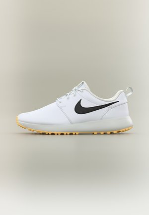 Chaussure de sport basse blanche avec le logo Nike noir, lacets blancs, et semelle texturée marron clair, vue de côté sur un fond uni.