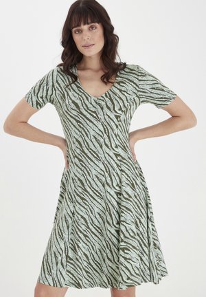 Kurzes grünes Kleid mit V-Ausschnitt, das mit einem Zebra-Streifenmuster in dunklerem Grün verziert ist. Ausgestellter Rock aus einem glatten, weichen Stoff.