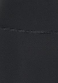 Black stretch fabric with a smooth texture, featuring contrasting stitching. The material has a soft, matte finish.