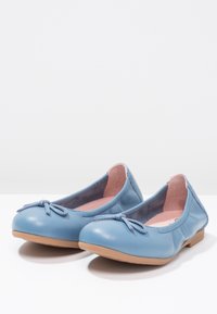Blaue Leder-Ballerinas mit einer runden Zehenpartie, einem kleinen Schleifchen vorne und einer tanfarbenen Gummisohle. Weiches pinkes Innenfutter.