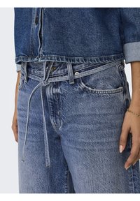 Jeans en denim bleu avec une coupe ample, dotés d'un cordon de serrage noué, d'un design à cinq poches, d'une texture vieillie et de coutures renforcées à la taille.