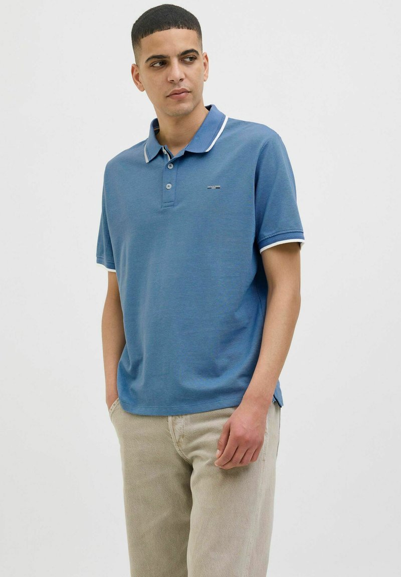 Pácolt kék pamut póló ing fehér gallérral és ujj díszítéssel. Rövid ujjú, laza fazonú, kis logóval a mellkason.