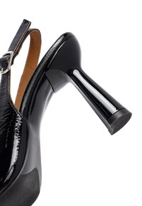 Scarpa con tacco alto in vernice nera, con punta affilata, finitura lucida e tacco affusolato e brillante. Inclusa una cinghia regolabile alla caviglia.