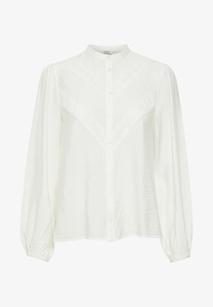 Hvid skjorte med knaplukning, der har en mandarin-krave, et struktureret V-mønster på stoffet, lange puffede ærmer og elastiske manchetter.